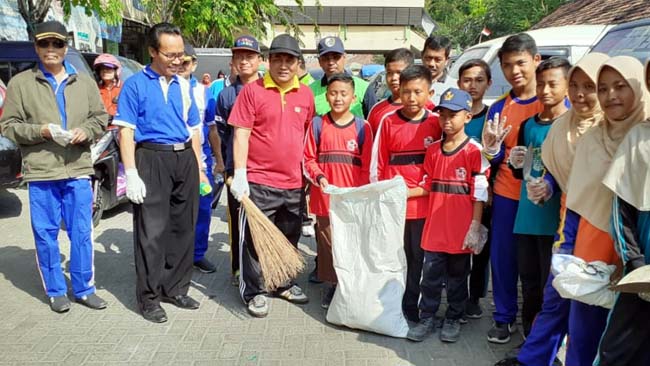 GOTONG ROYONG : Sekretaris Daerah Kabupaten Sampang Yuliadi Setiawan saat bersih-bersih di Pasar Srimangunan bersama para siswa dalam acara World Clean Up Day. (zyn)